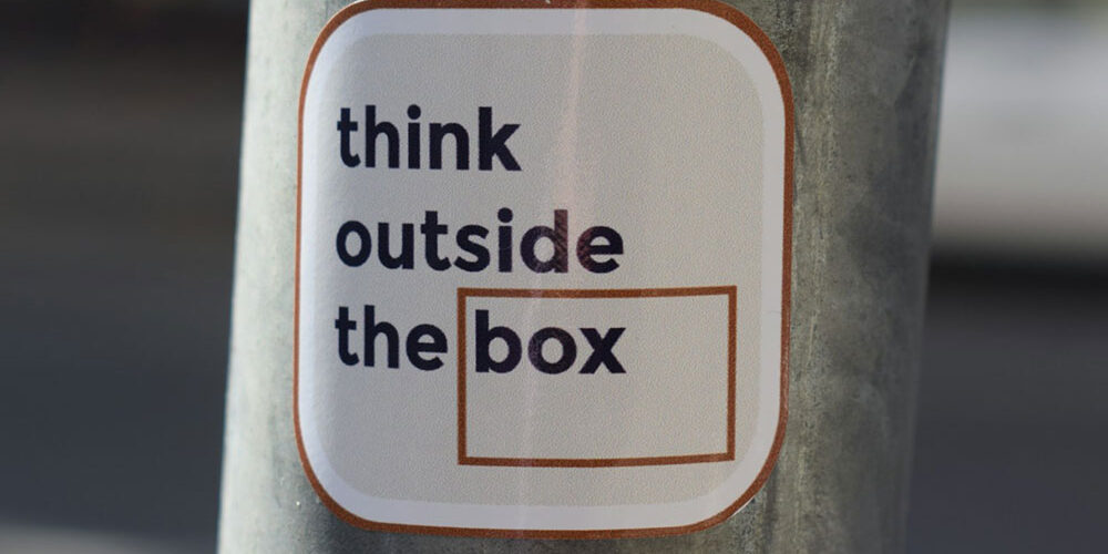 Sticker on a pole with the phrase 'think outside the box,' representing creative strategies in Boise SEO and content marketing.