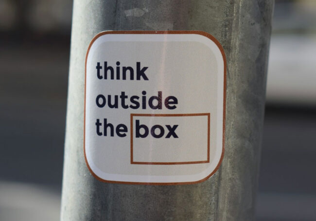 Sticker on a pole with the phrase 'think outside the box,' representing creative strategies in Boise SEO and content marketing.
